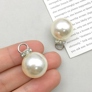 Gros plan d'un pendentif en perle blanche avec métal argenté et petits diamants