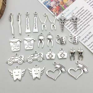 Detailed macro view of antique silver dental charms including toothbrush and ambulance
