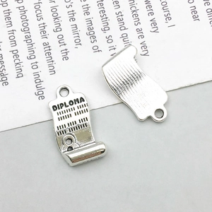 Macro detail of silver diploma charm showing engraved text and textured back for DIY jewelry