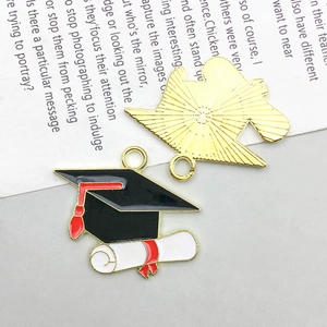 Detail of graduation cap and diploma charms with black and red enamel on gold alloy
