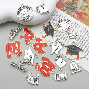 Macro detail of graduation themed alloy charms with black and red enamel finish for DIY jewelry