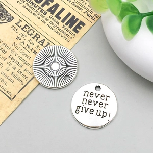 Vista dettagliata dei ciondoli tondi in argento antico con incisione Never Give Up per DIY