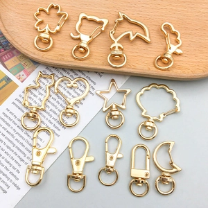 Nahaufnahme goldener Karabinerhaken in Herz- und Sternform auf einem Holztablett für DIY