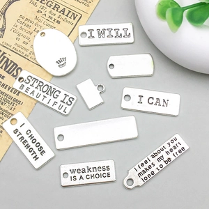 Primer plano de colgantes de plata con letras inspiradoras para creación de joyas DIY