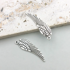 Macro detail of antique silver alloy angel wing charms with intricate feather textures