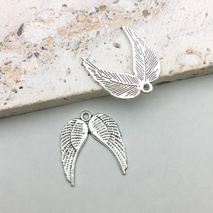 Detailed view of antique silver alloy angel wing charms with intricate feather textures