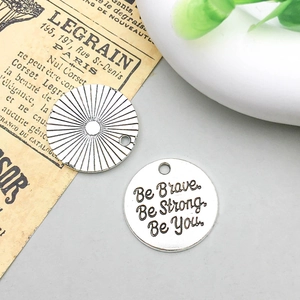 Vista macro di ciondoli in argento antico con incisione Be Brave Be Strong Be You