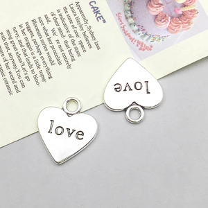 Detailansicht der silbernen Herzanhänger mit eingraviertem Love-Schriftzug und Ösen
