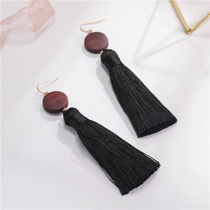 Detail of bohemian long black fringe earrings with dark wood disks and gold hooks