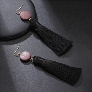 Close-up of bohemian earrings with dark wood beads and long black silky tassels