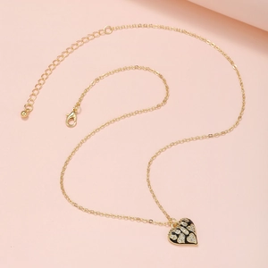 Makroaufnahme von Herzanhänger mit schwarzem Emaille und Zirkonia an goldener Kette