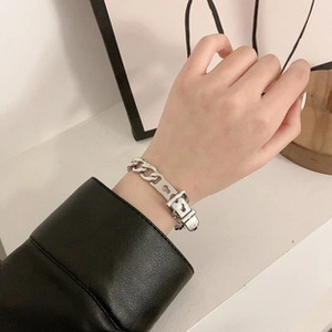 Detail of silver chain bracelet featuring a belt buckle clasp and heart cutout