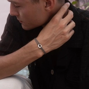 Close-up of minimalist grey cord bracelet with silver hexagonal nut-shaped metal buckle