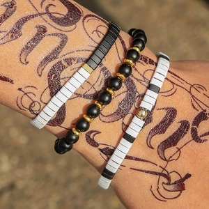 Primer plano del set de tres pulseras de cuentas Tila con detalles en blanco y negro en la muñeca