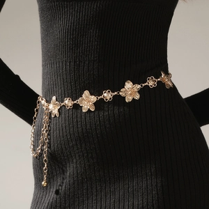 Detail of adjustable gold floral waist chain with tassels on a black knit dress
