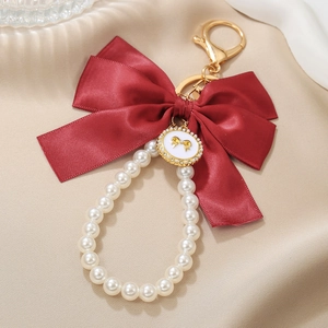 Deep red satin bow keychain with white faux pearl loop and gold rhinestone pendant