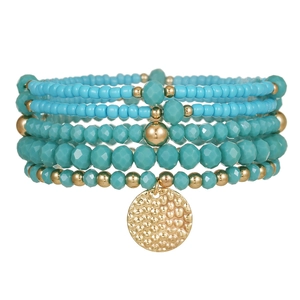 Detail van boho-armband met turquoise glazen kralen en een gehamerde gouden hanger