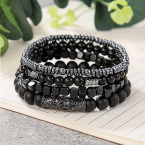 Macro detail of multi-layer black beaded bracelet with engraved vintage metal cylinder