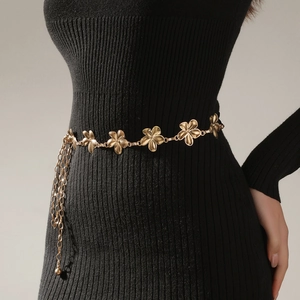 Close-up of golden metal floral waist chain with tassels on a black dress