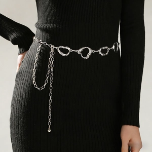 Close-up of silver metal waist chain with heart-shaped links on a black dress