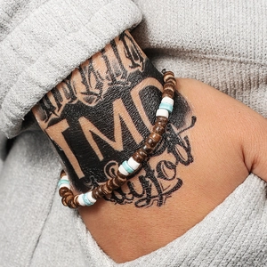 Detail van kralenarmband met donker hout, witte en blauwe kralen om de pols van een model