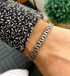 Detail van geweven roestvrijstalen herenarmband met zwarte hematiet steen kralen