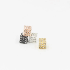 Macro detail of rhinestone-encrusted dice-shaped beads in gold, silver, black, and rose gold