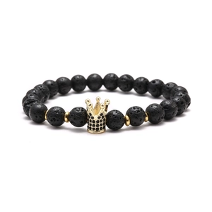 Macro detail of natural black lava stone beads and a gold crown charm with black zircons