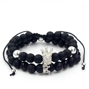 Detailed macro view of black lava stone beaded bracelet with a silver crown charm
