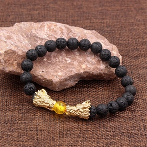 Dettaglio del ciondolo a testa di drago su bracciale in pietra lavica nera e perla gialla