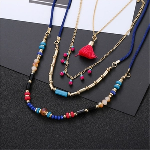 Detail of bohemian layered necklace with colorful beads and a vibrant red tassel pendant