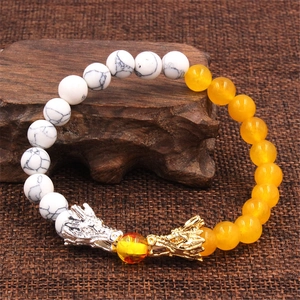 Dettaglio macro delle teste di drago sul bracciale di perle di marmo e ambra