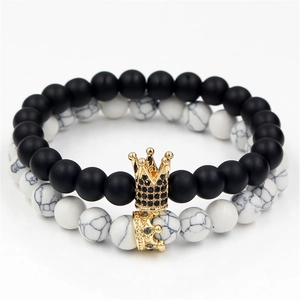 Close-up of matte black and white marble stone bracelets with golden crowns charms