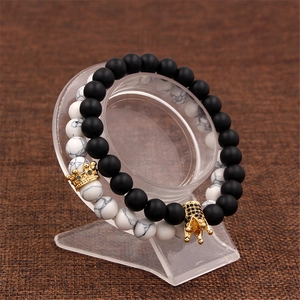 Detail of matte black and white turquoise crown bracelets on acrylic display stand