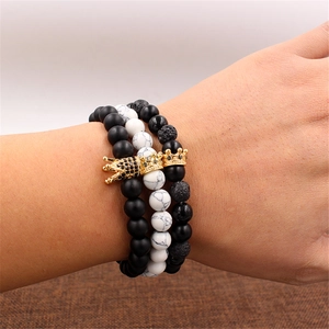 Detailed shot of three beaded bracelets with matte stones and golden crown charms