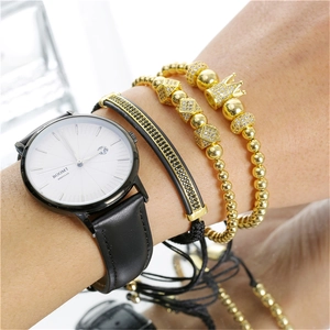 Detailopname van herenhorloge met zwart leer en gelaagde gouden kroon kralenarmbanden