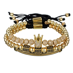 Detalle de pulseras de cuentas negras ajustables con corona dorada y circonitas micro-pave