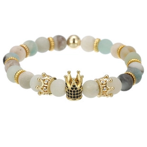 Detailed macro view of green and beige beaded bracelet with golden crown charm and black zircon