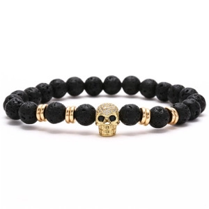 Macro detail of natural lava rock beads and a gold skull pendant with sparkling zircons