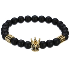 Detailed macro view of black matte stone beads and golden crown charm on elastic bracelet