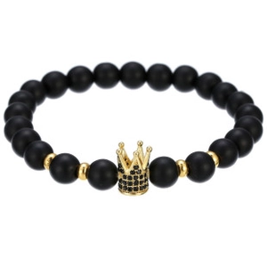 Macro detail of matte black beads with gold micro-pave crown charm and steel spacers