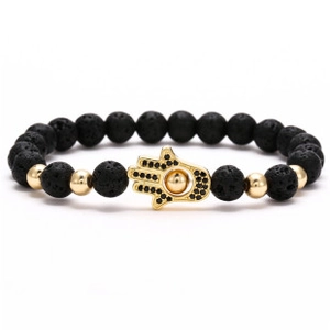 Macro detail of 8mm black lava stone beads and golden Hamsa Hand charm on bracelet