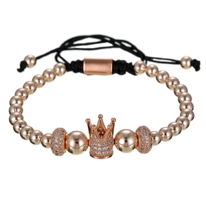 Macro-detail van de roségouden kroon-bedelarmband met zirkonia en gevlochten koord