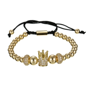 Detail van gouden kralenarmband met zirkonia kroon en verstelbaar zwart gevlochten koord