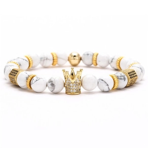 Macro detail of a white marble bead bracelet with a gold crown charm and crystals