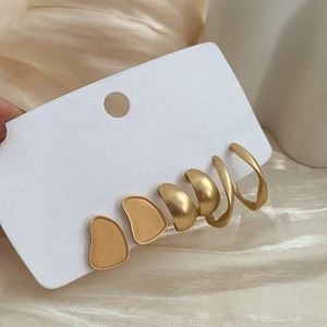 Three-pair matte gold earring set featuring pebble studs and minimalist twist hoops on card