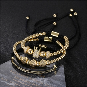 Driedelige gouden kralenarmbandset met kroon- en zirkonia-bedels op een zwarte basis