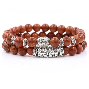 Close-up of red-brown sandstone bead bracelet with vintage Buddha head and metal tube