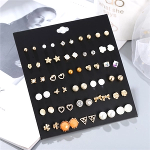 Dettaglio di un set di 30 paia di orecchini dorati con perle e strass su scheda nera