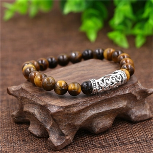 Macro detail of tiger eye beaded bracelet with vintage silver filigree metal tube